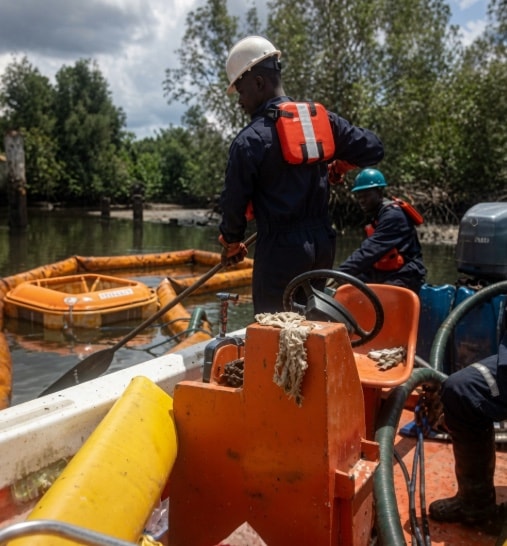 Response crew deploying containment booms from a boat
